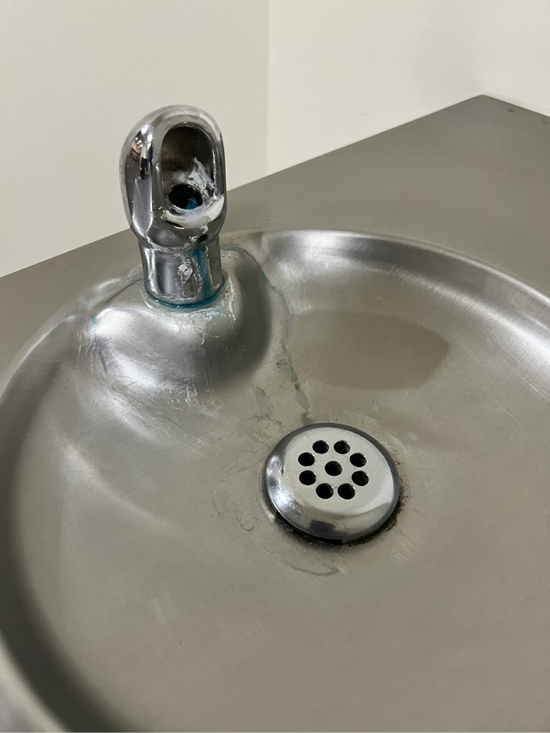 A water fountain with a faucet that looks like a screaming face.