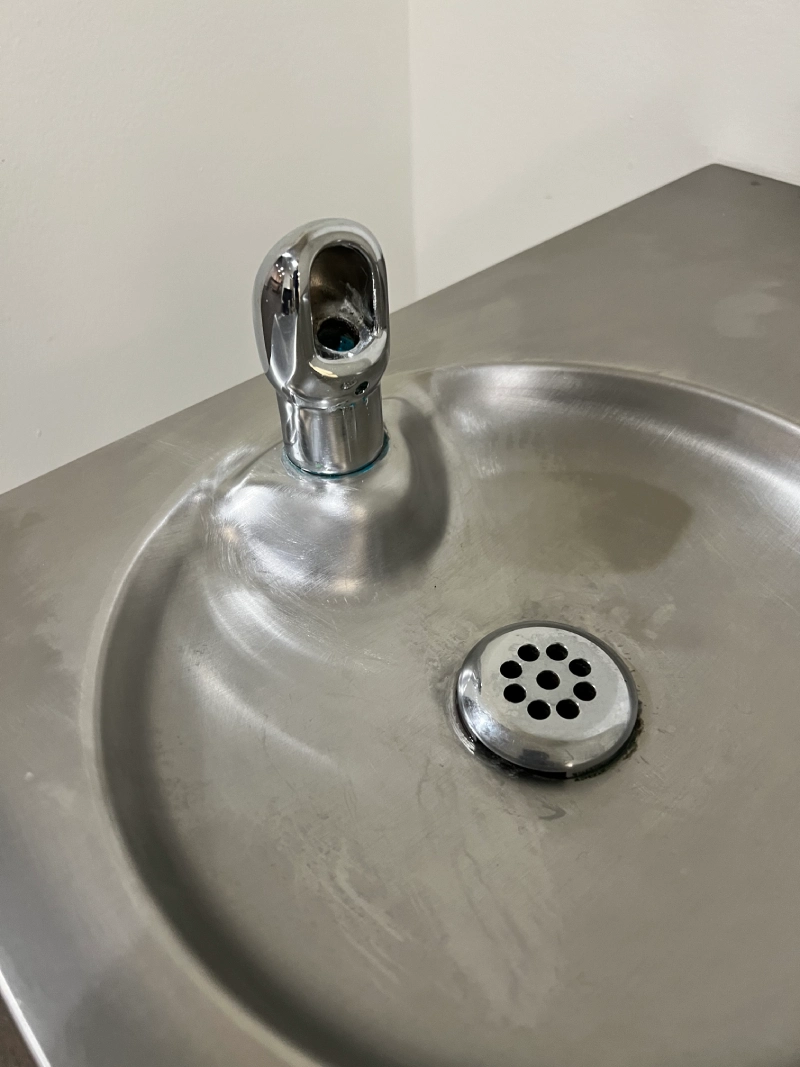 A stainless steel drinking fountain with a rounded water spout.