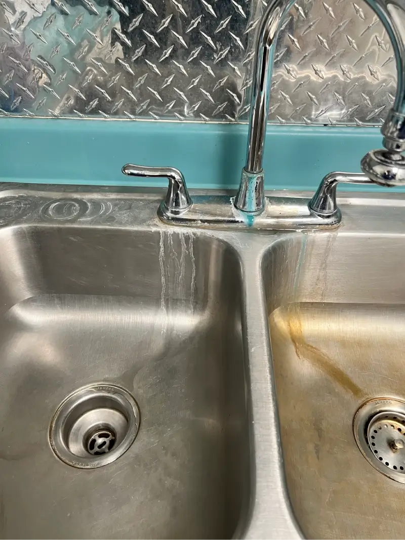Side-by-side stainless steel kitchen sinks, one clean and one stained.
