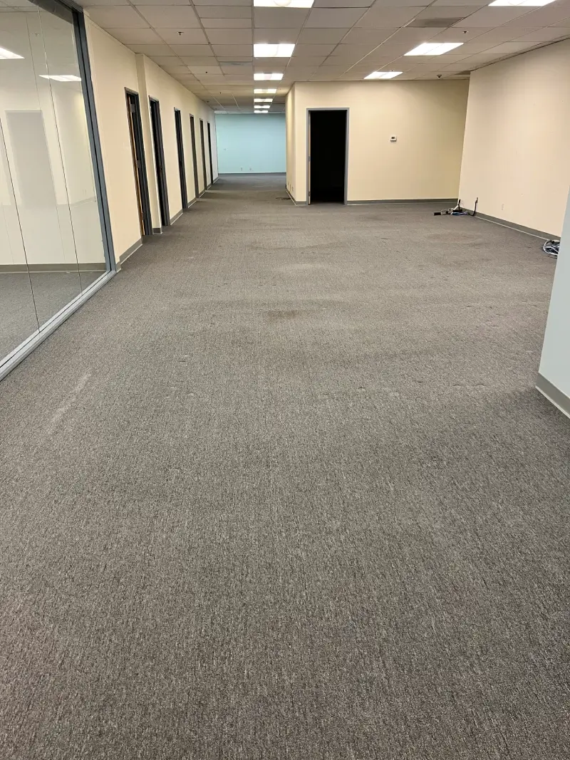 Empty room with gray carpet flooring and mirrored wall.
